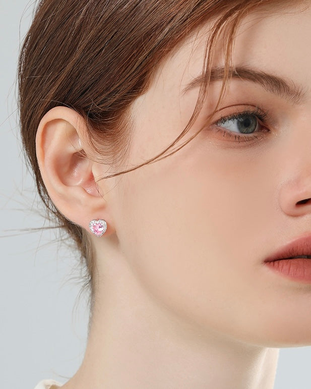 Close-up of a woman wearing pink heart-shaped earrings against a light background