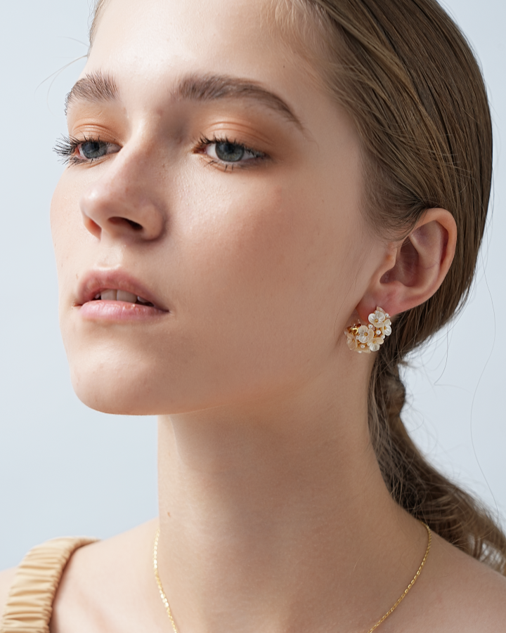 Woman wearing gold earrings and necklace against a light background