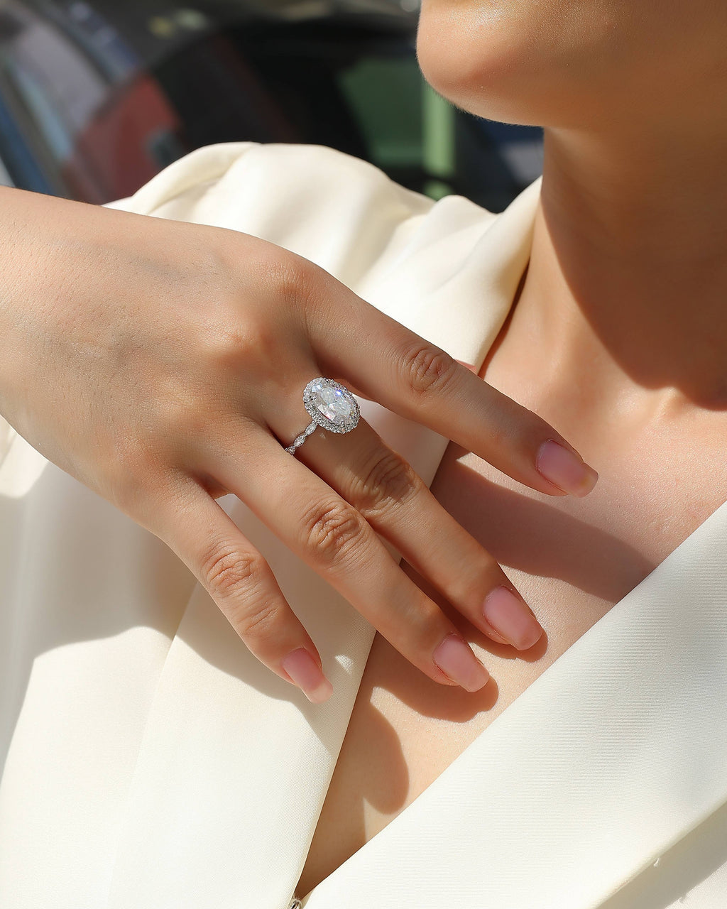 Close-up of a hand wearing a diamond ring with a blurred background