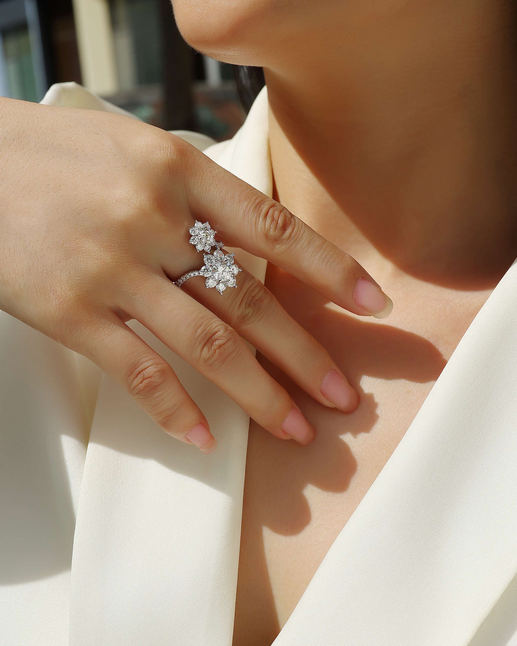 Close-up of a hand wearing a diamond ring and earring on a blurred background