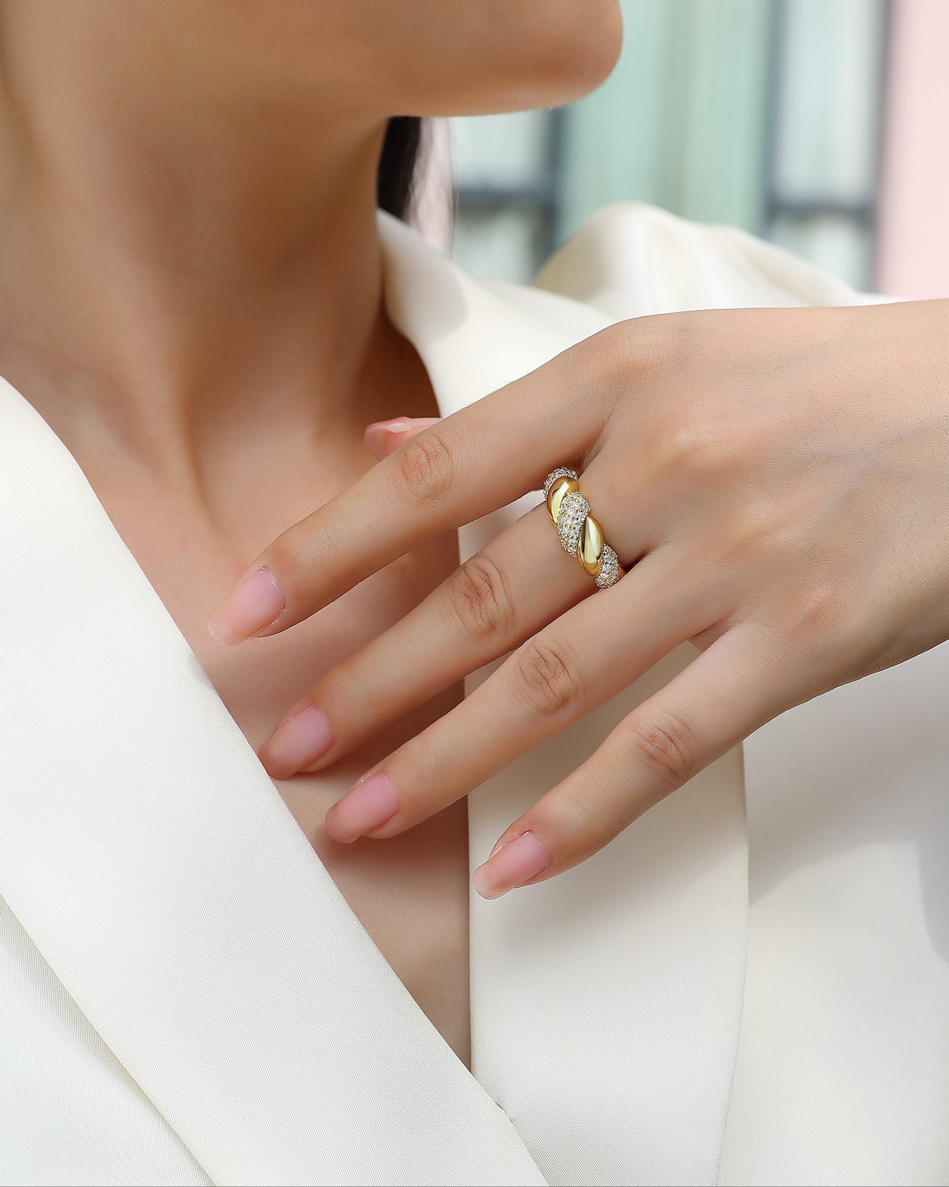 Close-up of a hand wearing a gold ring with a blurred background