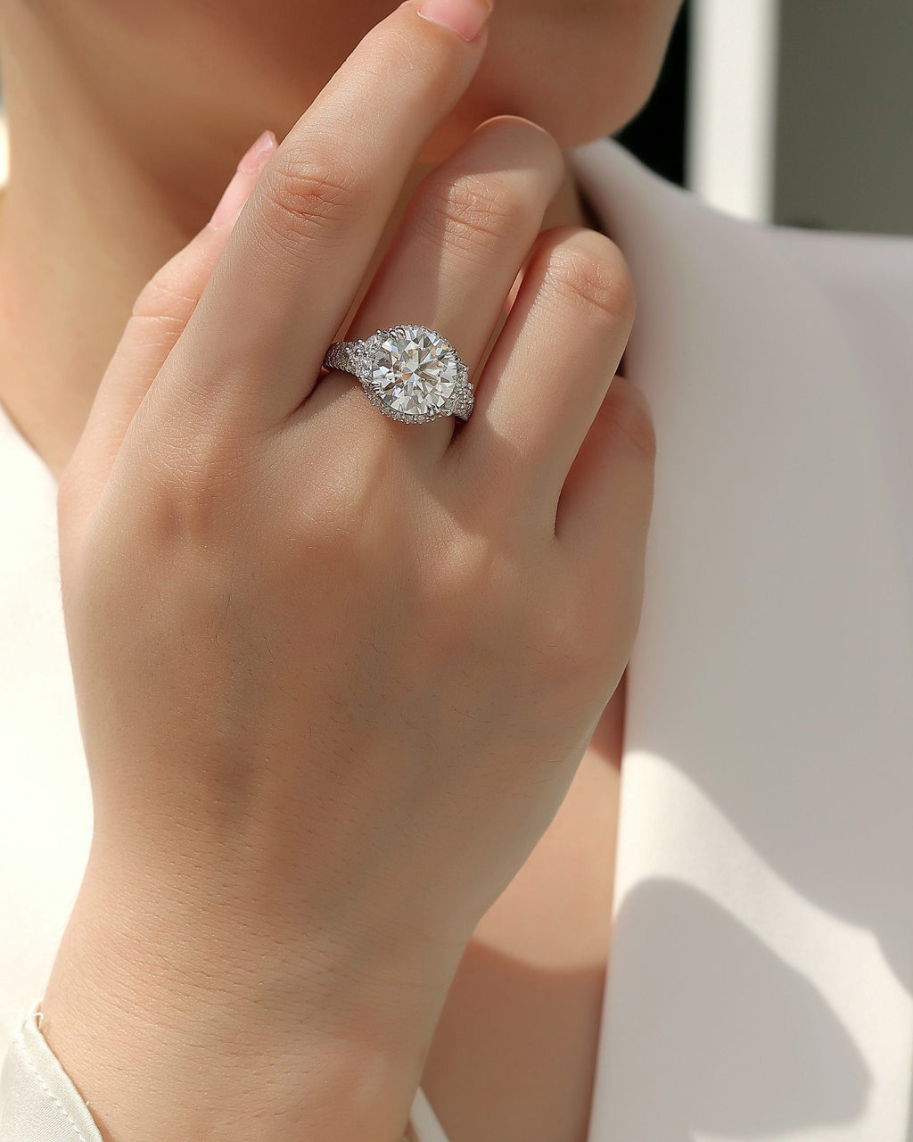 Close-up of a hand wearing a diamond ring with a blurred background