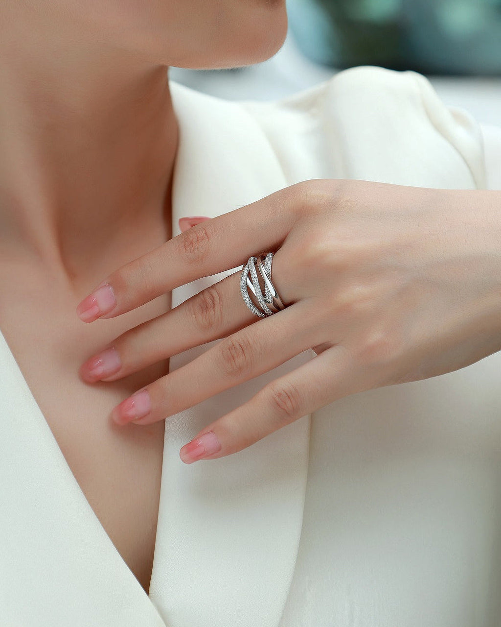 Close-up of a hand wearing a silver ring with a blurred background