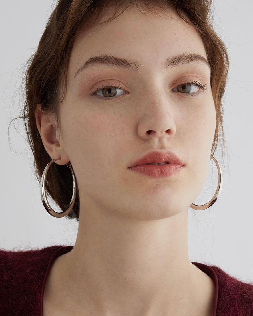 Woman wearing gold hoop earrings against a plain background
