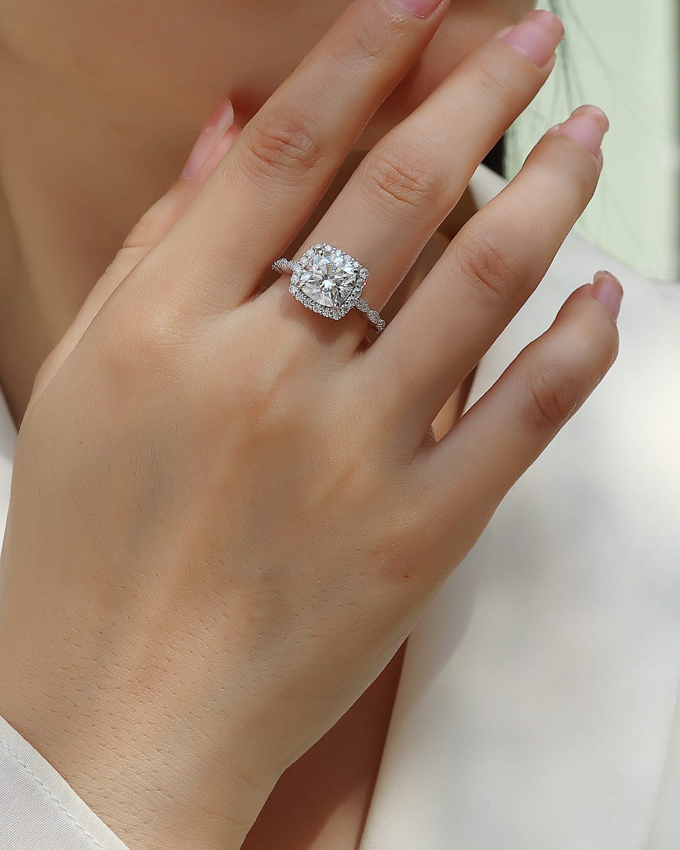 Close-up of a hand wearing a diamond ring with a blurred background