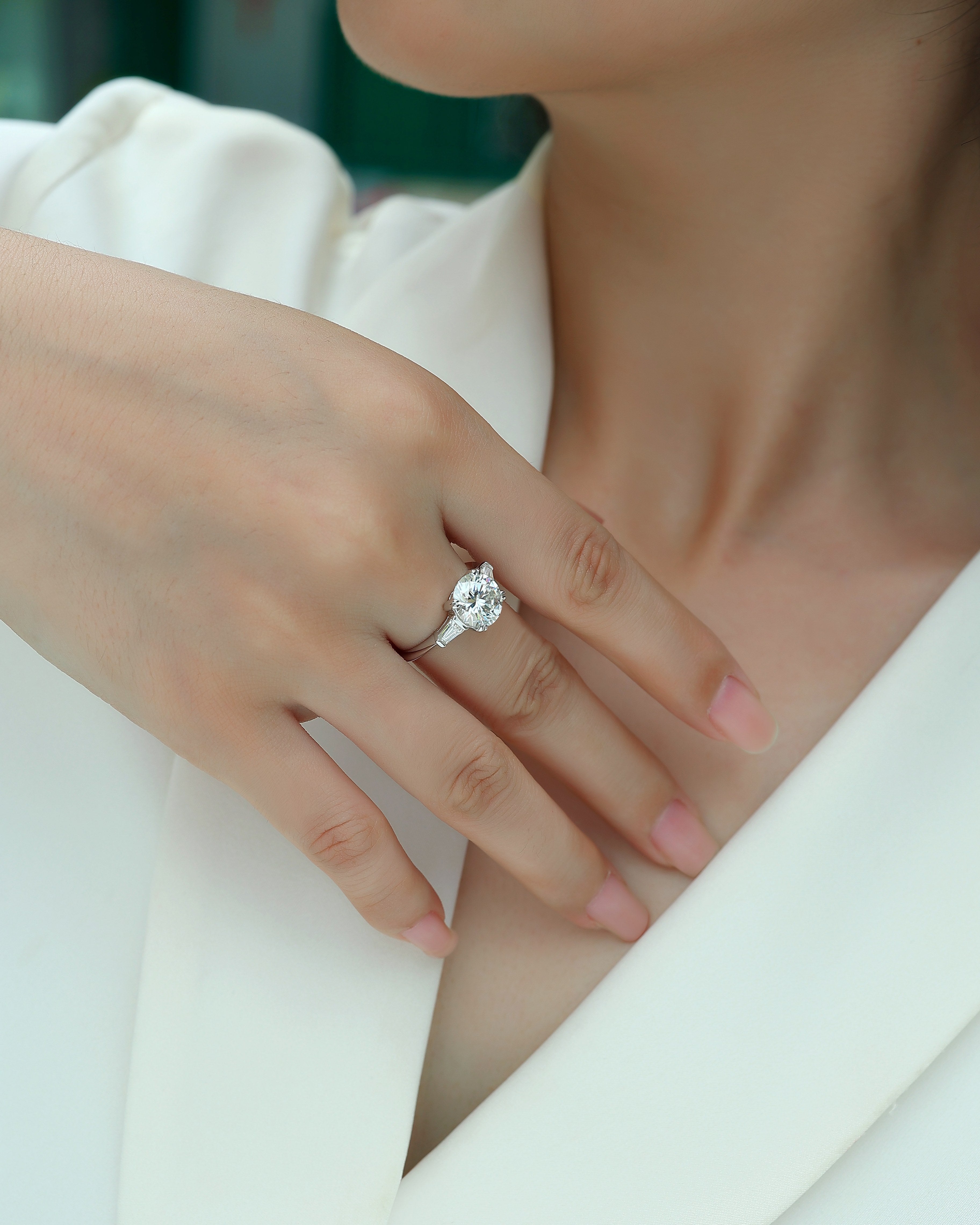 Close-up of a hand wearing a diamond ring on a blurred background