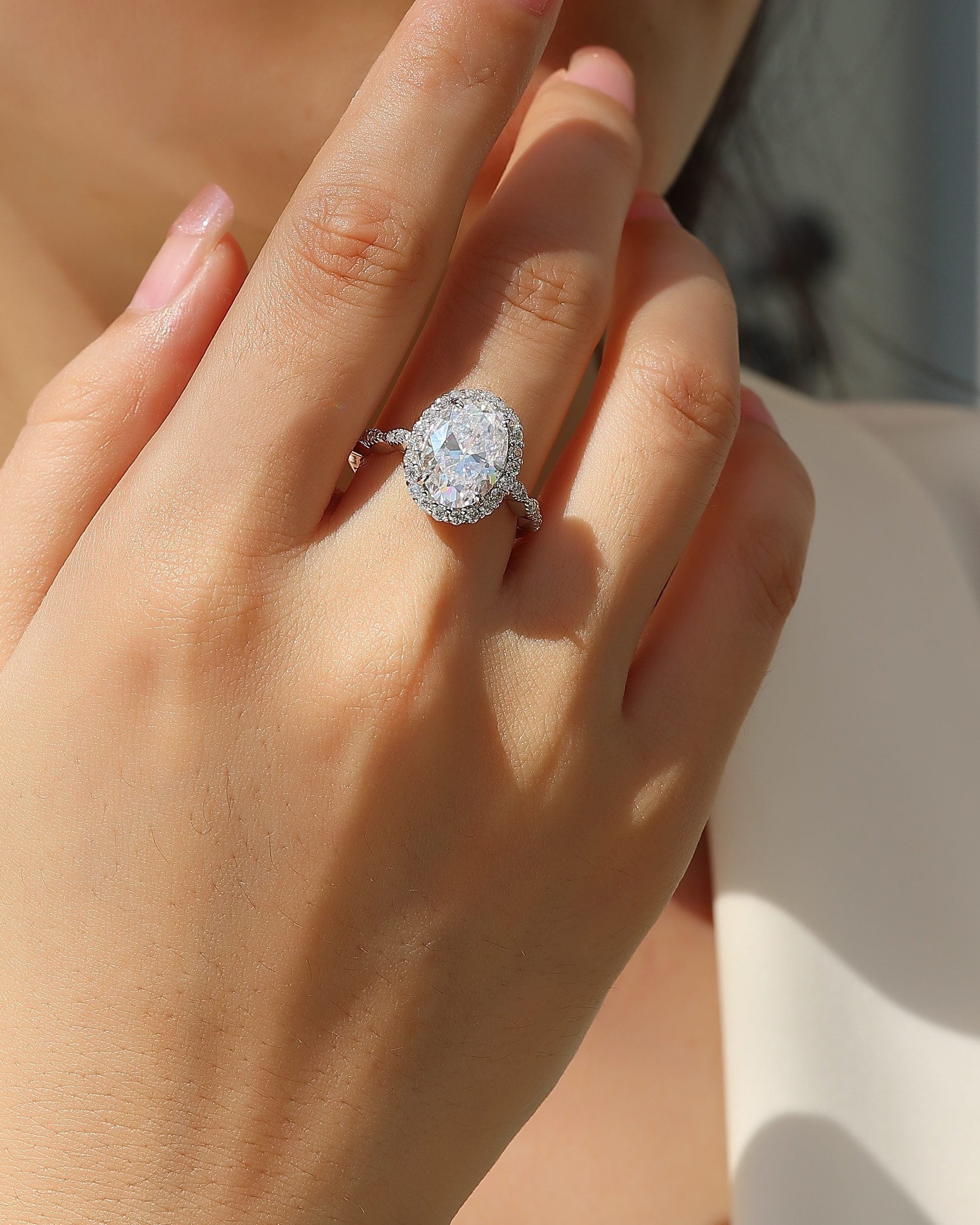 Close-up of a hand wearing a diamond ring with a blurred background