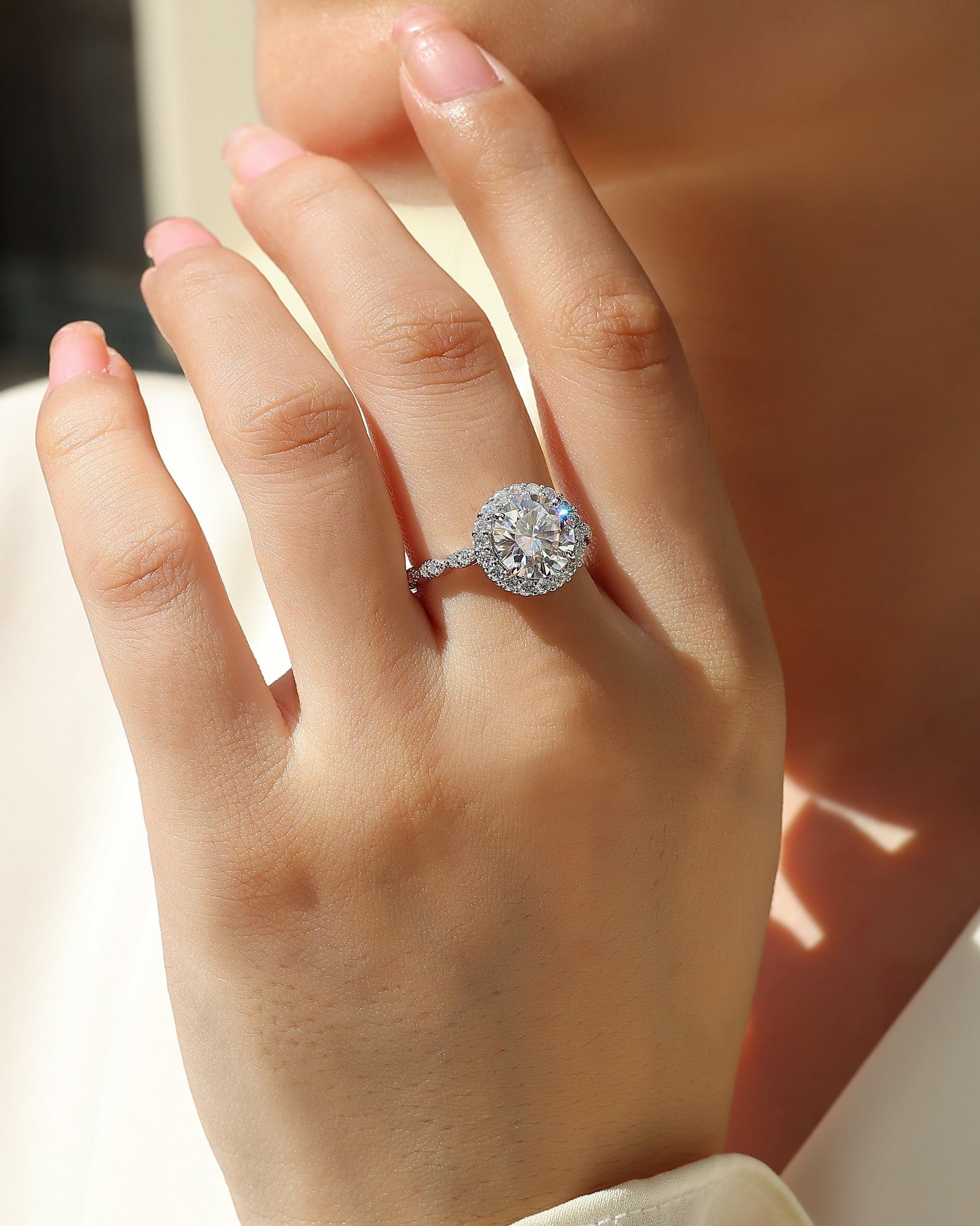 Close-up of a hand wearing a diamond ring with a blurred background