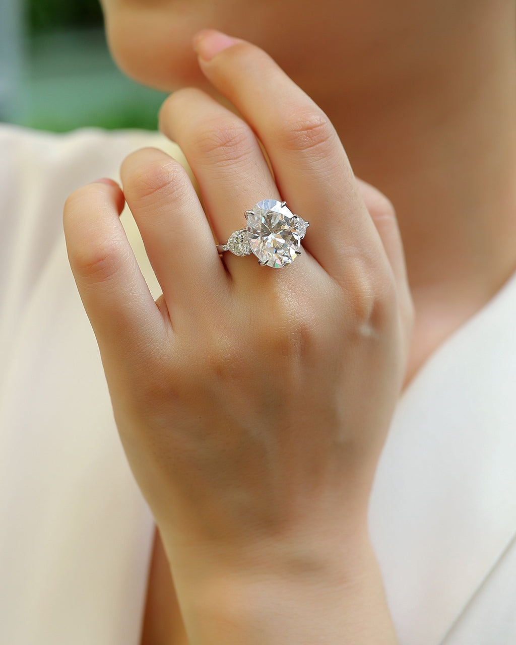 Close-up of a hand wearing a diamond ring with a blurred background
