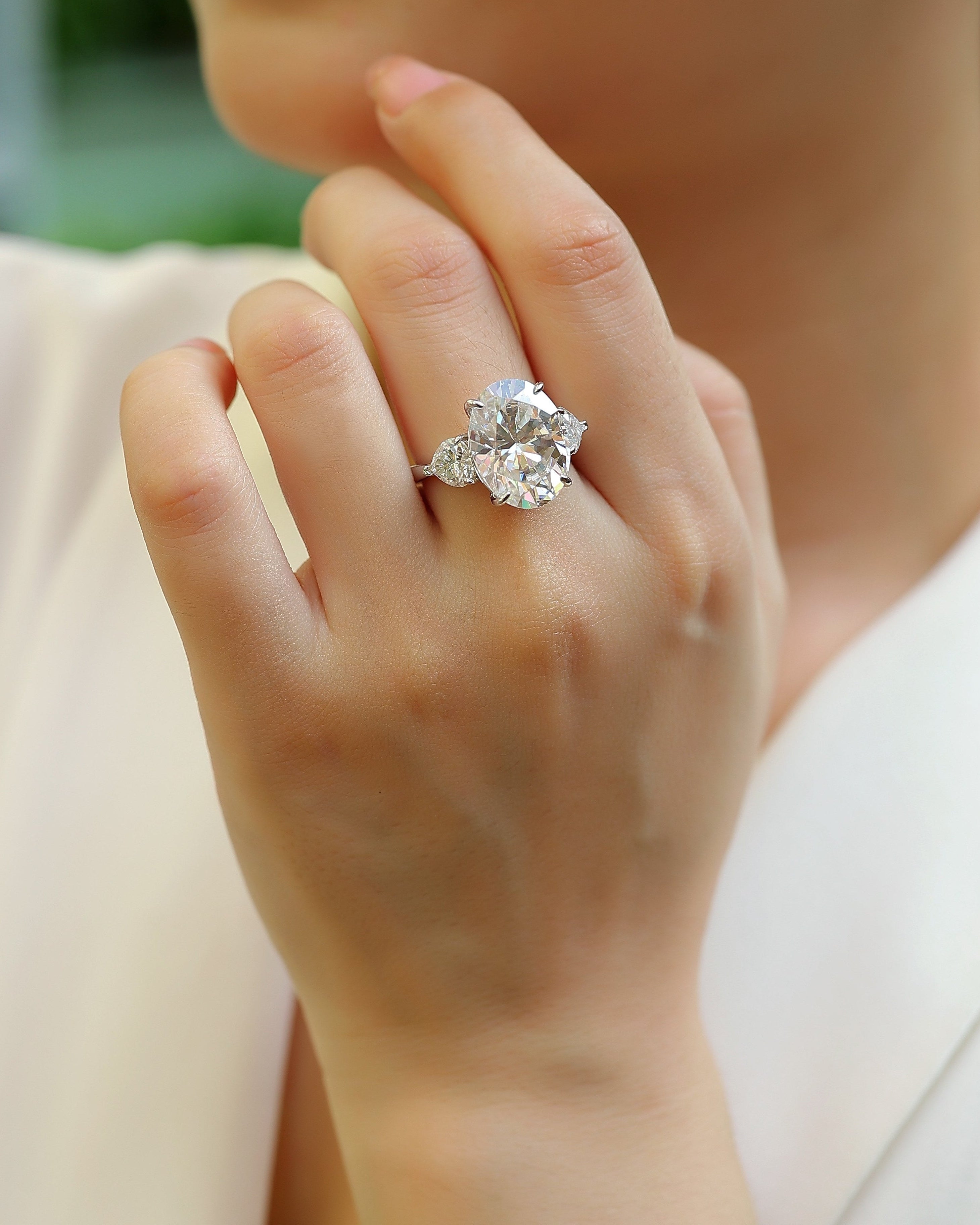 Close-up of a hand wearing a diamond ring with a blurred background