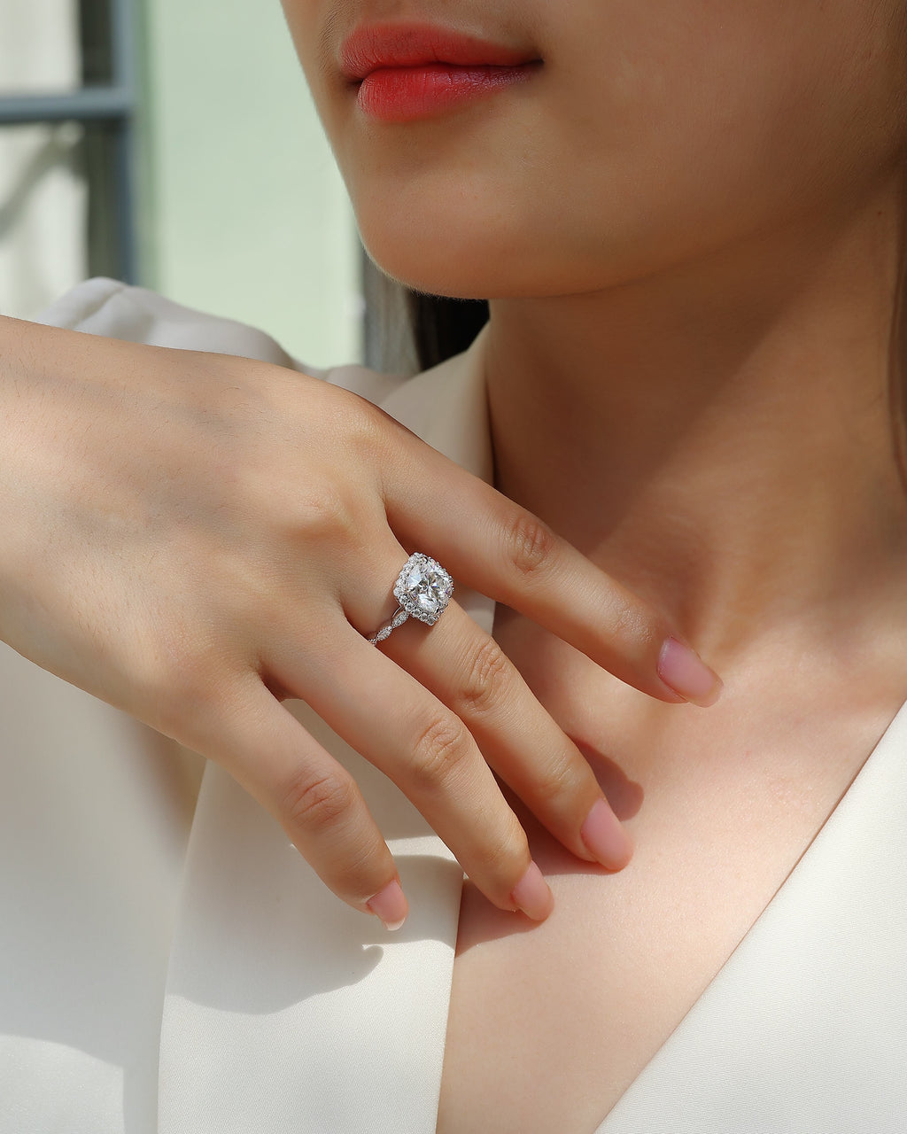 Close-up of a woman's hand wearing a diamond ring with a blurred background