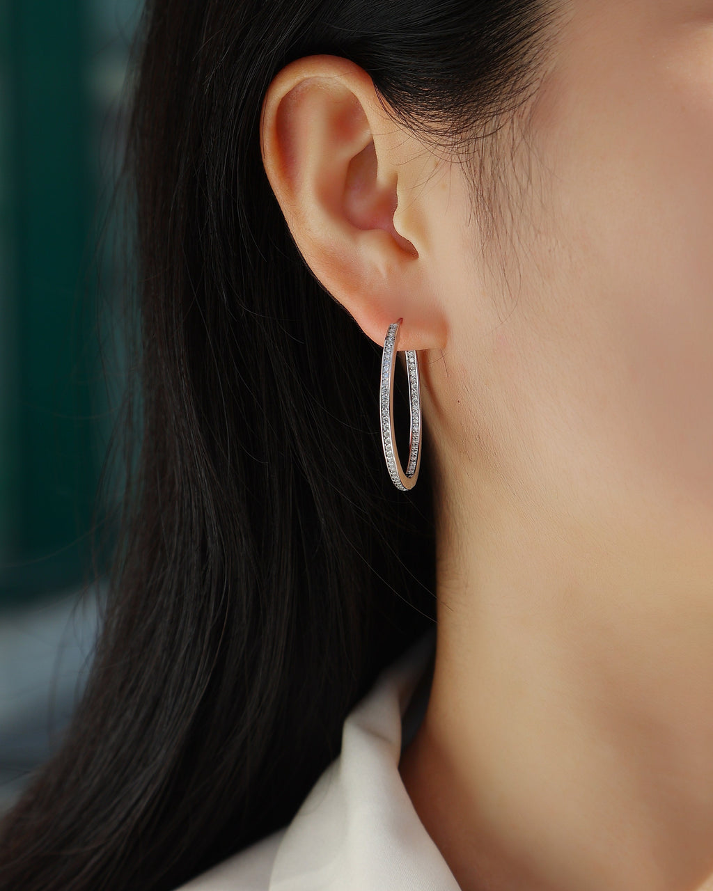 Close-up of a person wearing a silver hoop earring with a blurred background