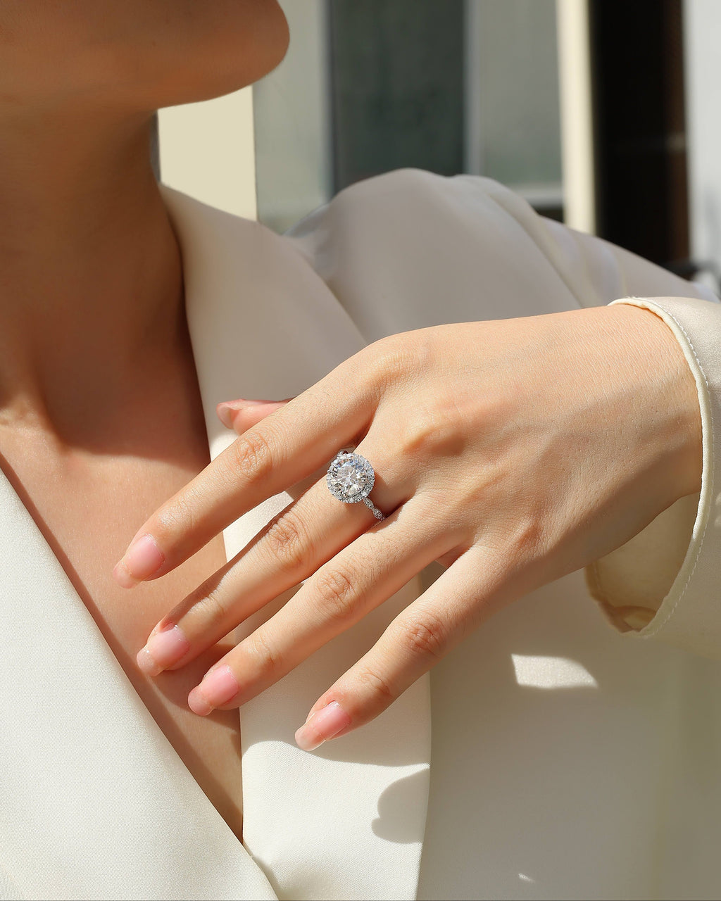 Close-up of a hand wearing a diamond ring with a blurred background