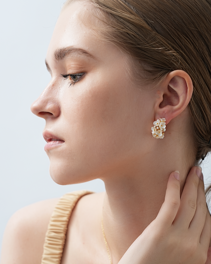 Woman wearing a gold earring with a light background