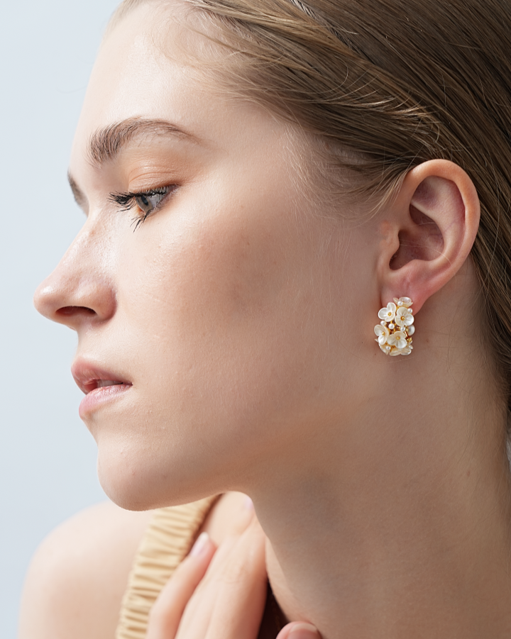 Close-up of a woman wearing floral earrings with a light background