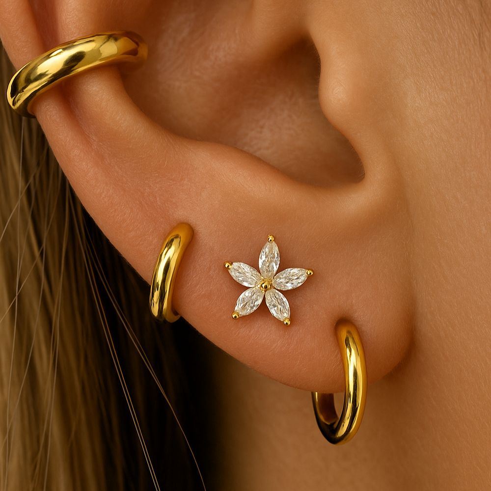 Close-up of an ear with gold hoop earrings and a diamond flower earring.