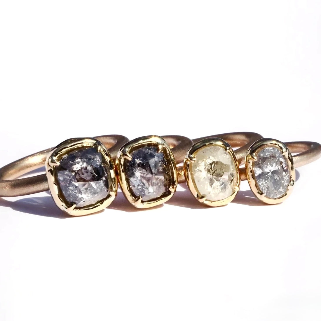 Gold ring with four oval-cut diamonds on a white background