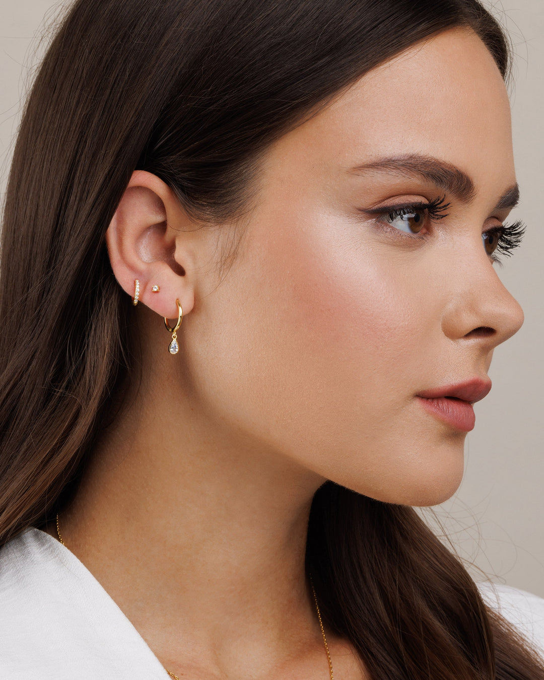 Close-up of a woman wearing gold earrings with a neutral background