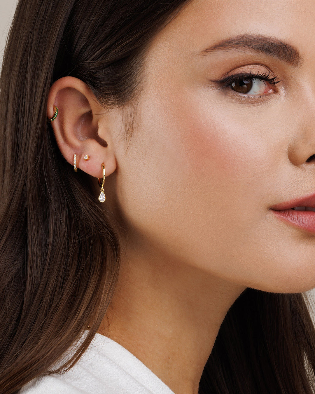 Close-up of a woman wearing gold hoop earrings with a pearl drop earring.