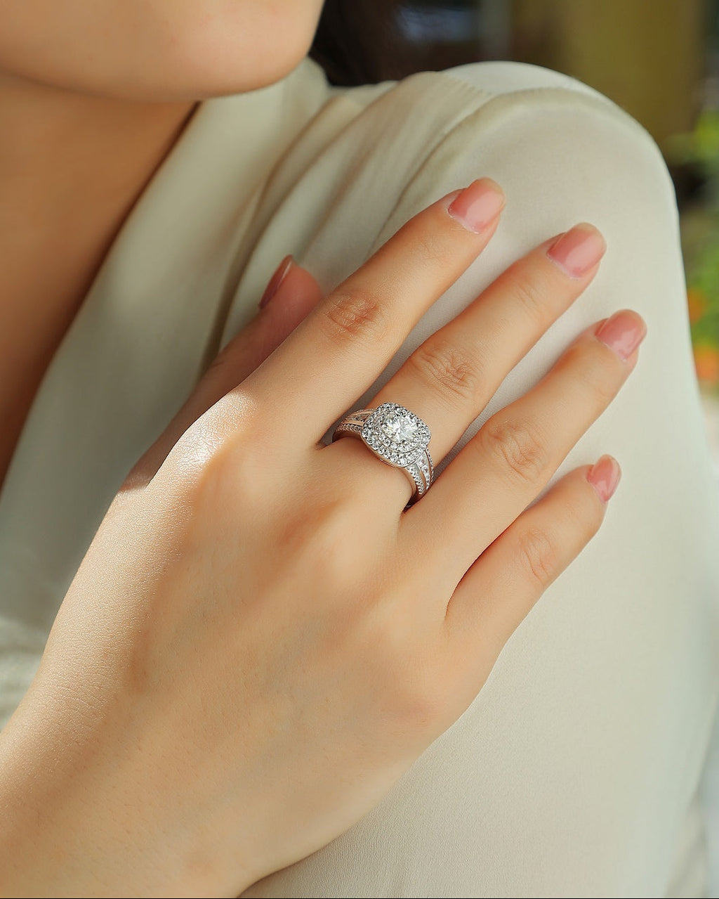Close-up of a hand wearing a diamond ring with a blurred background