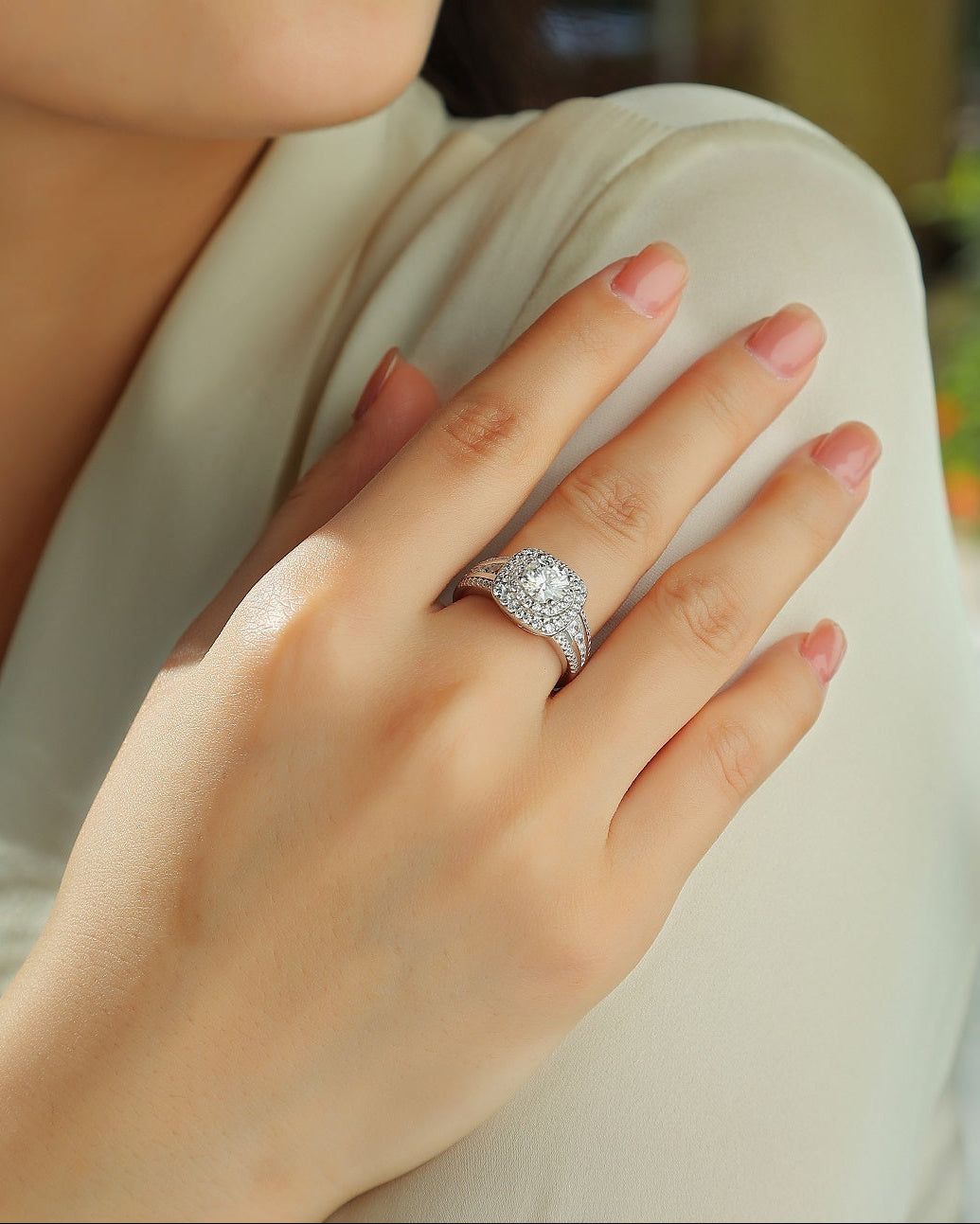 Close-up of a hand wearing a diamond ring with a blurred background