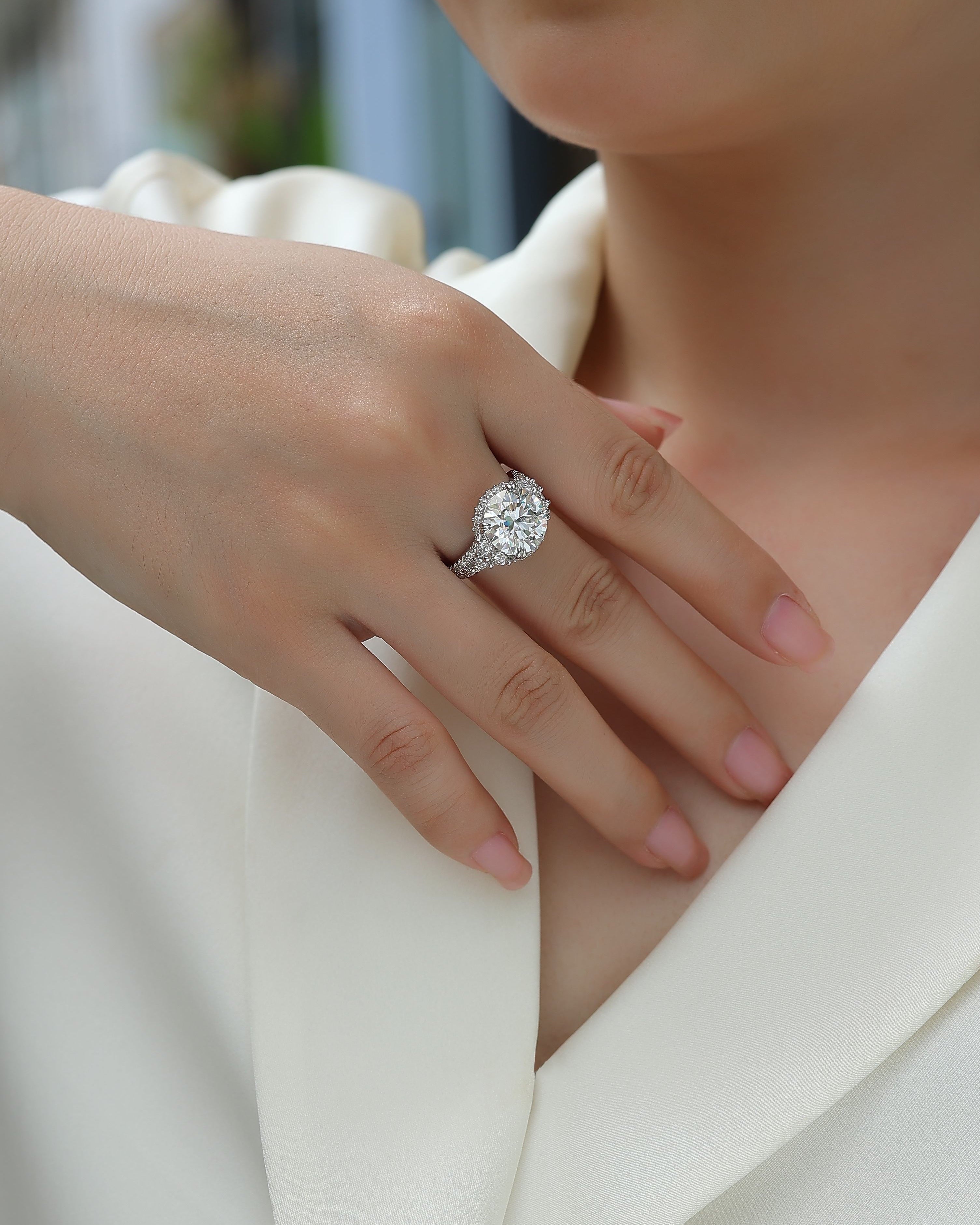 Close-up of a hand wearing a diamond ring with a blurred background