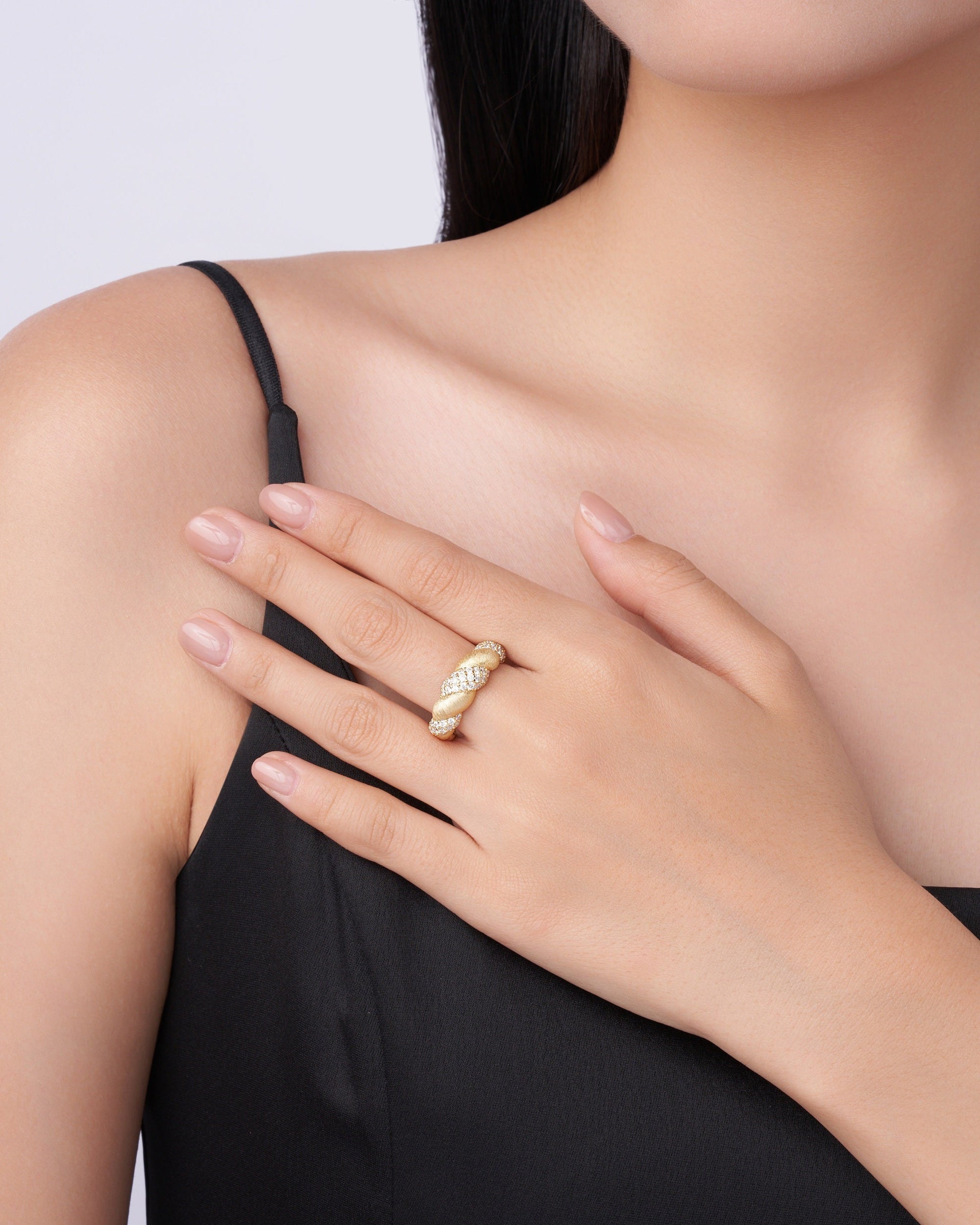 Woman wearing a gold ring on her hand against a neutral background