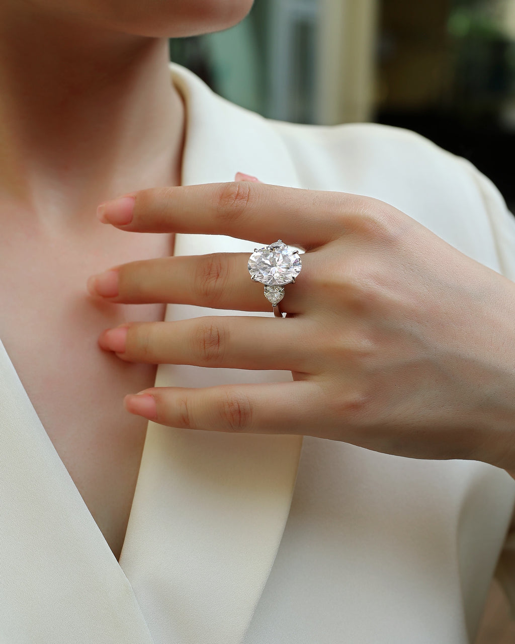 Close-up of a hand wearing a diamond ring with a blurred background