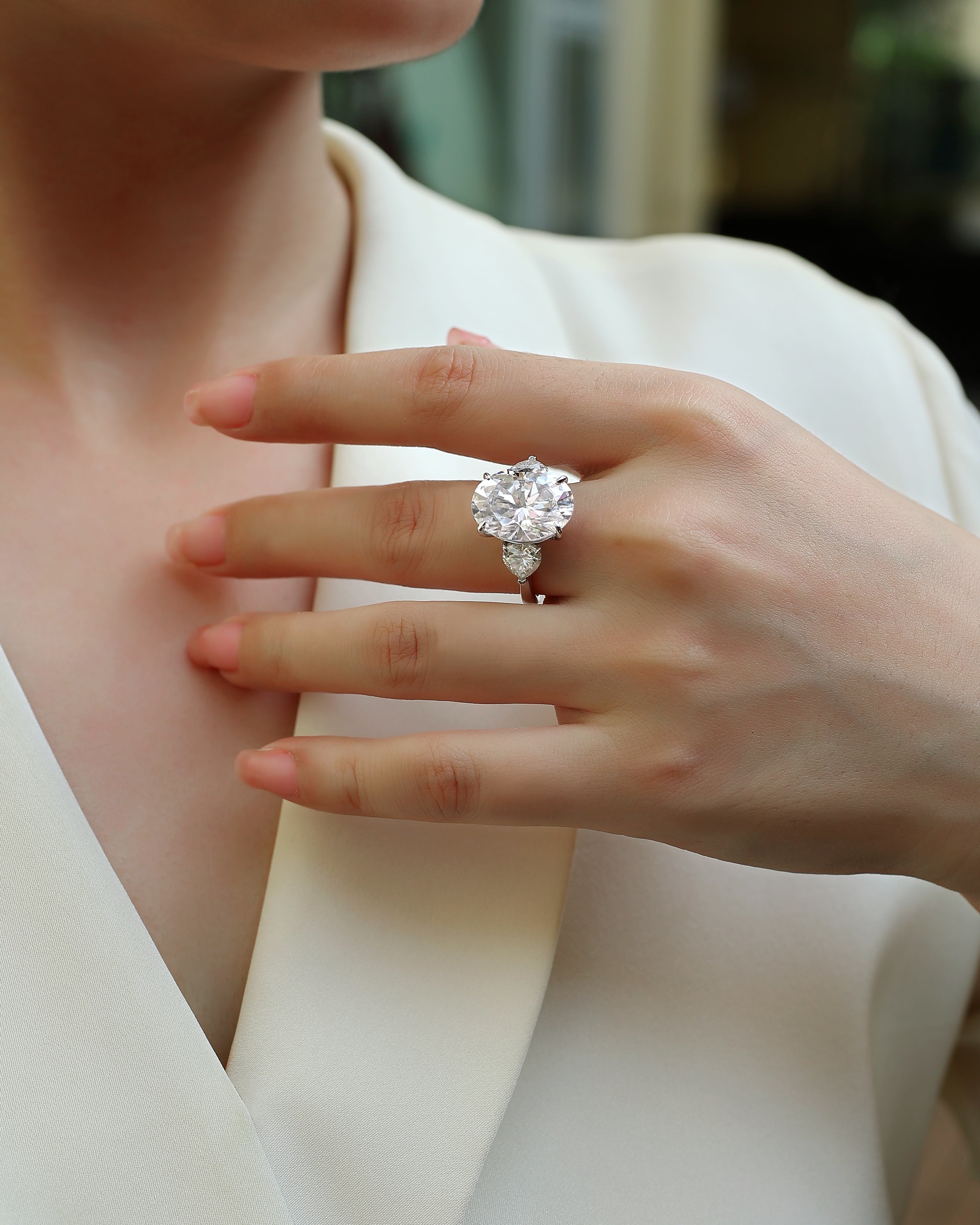 Close-up of a hand wearing a diamond ring with a blurred background