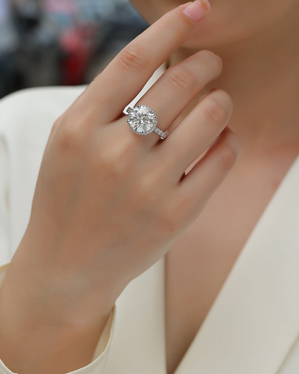 Close-up of a hand wearing a diamond ring with a blurred background