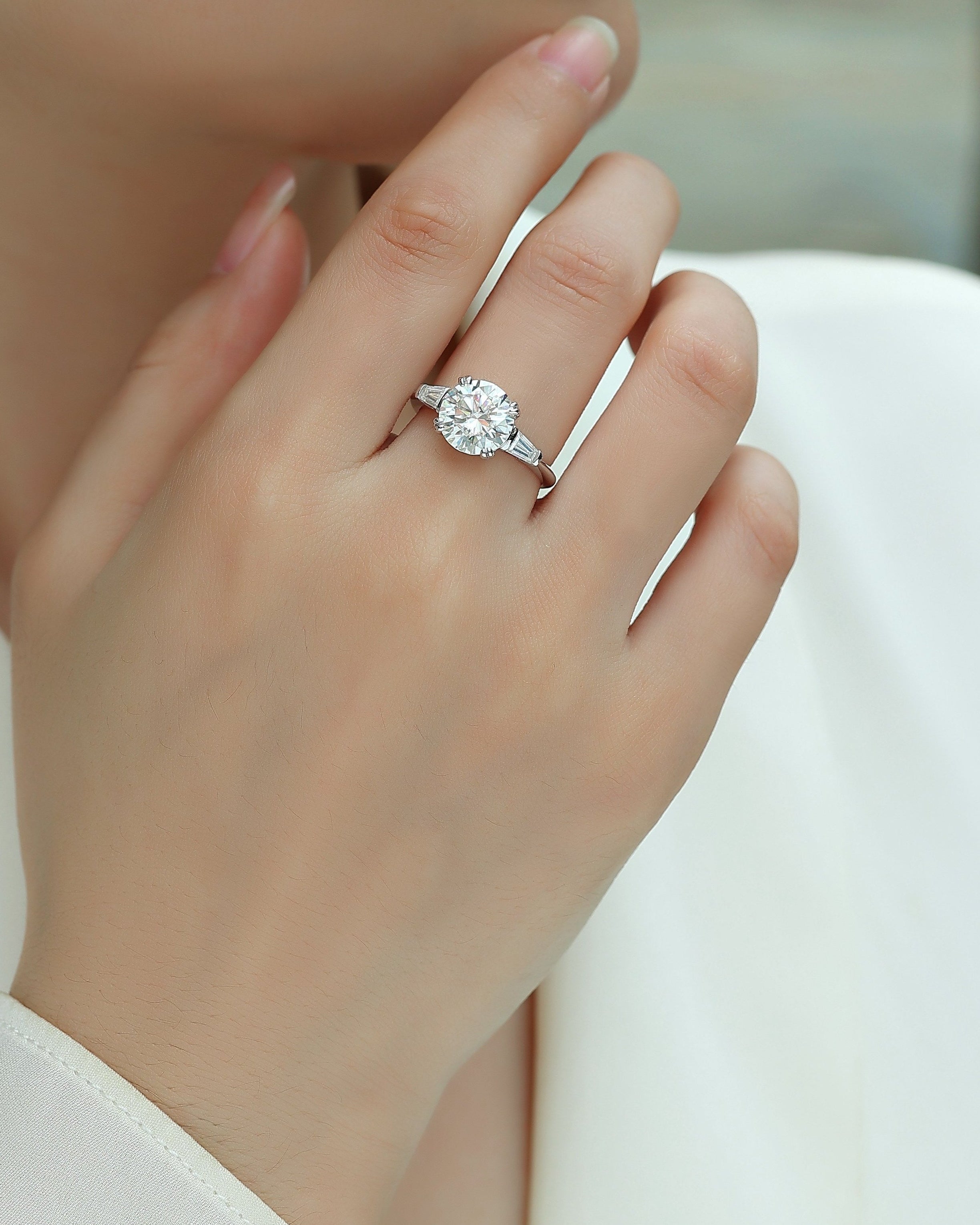 Close-up of a hand wearing a diamond ring with a blurred background