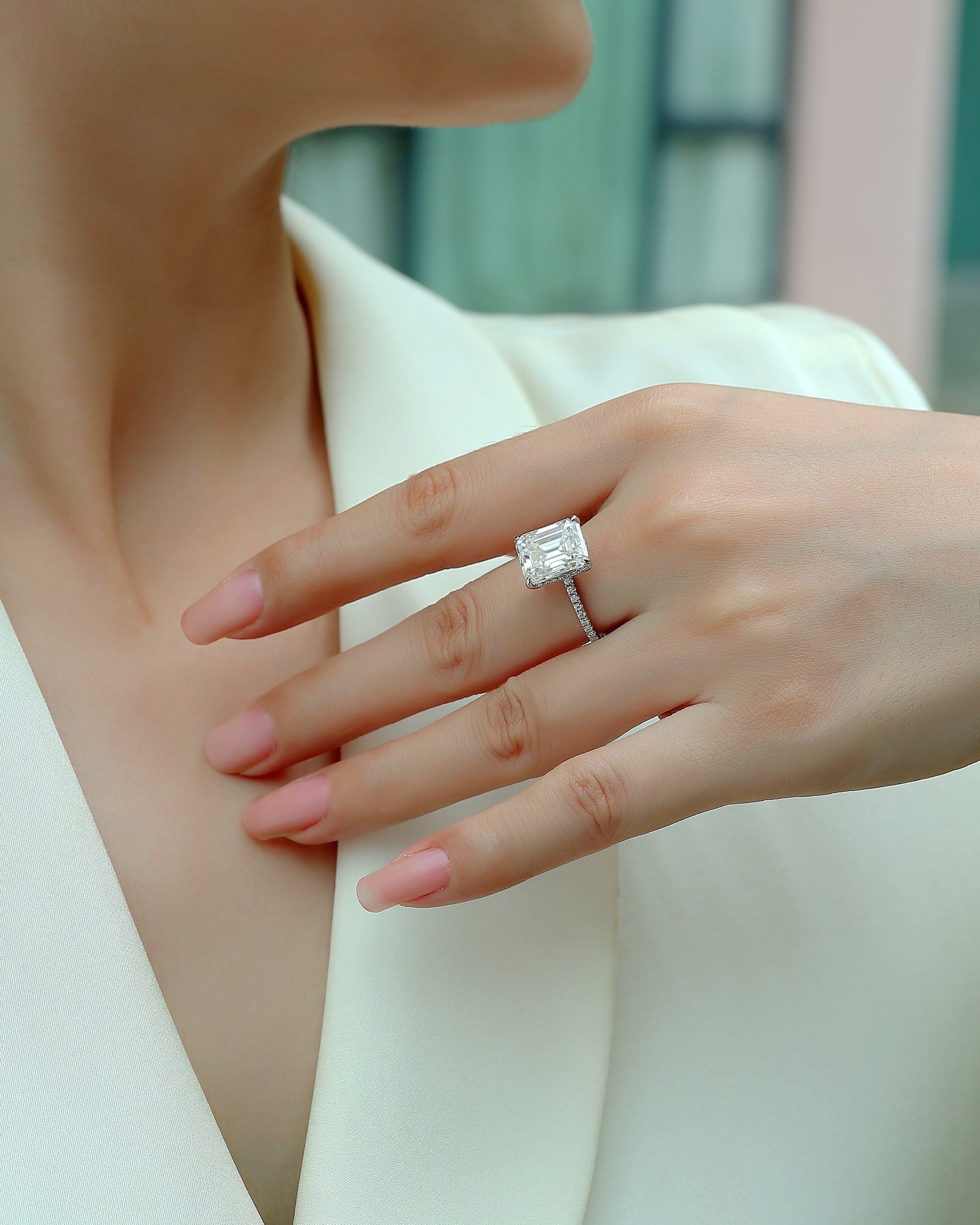 Close-up of a hand wearing a diamond ring with a blurred background