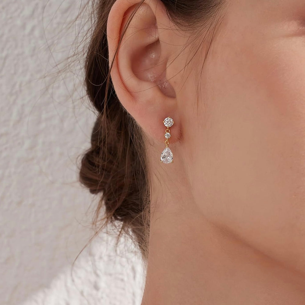 Close-up of a person wearing a pair of earrings with a neutral background