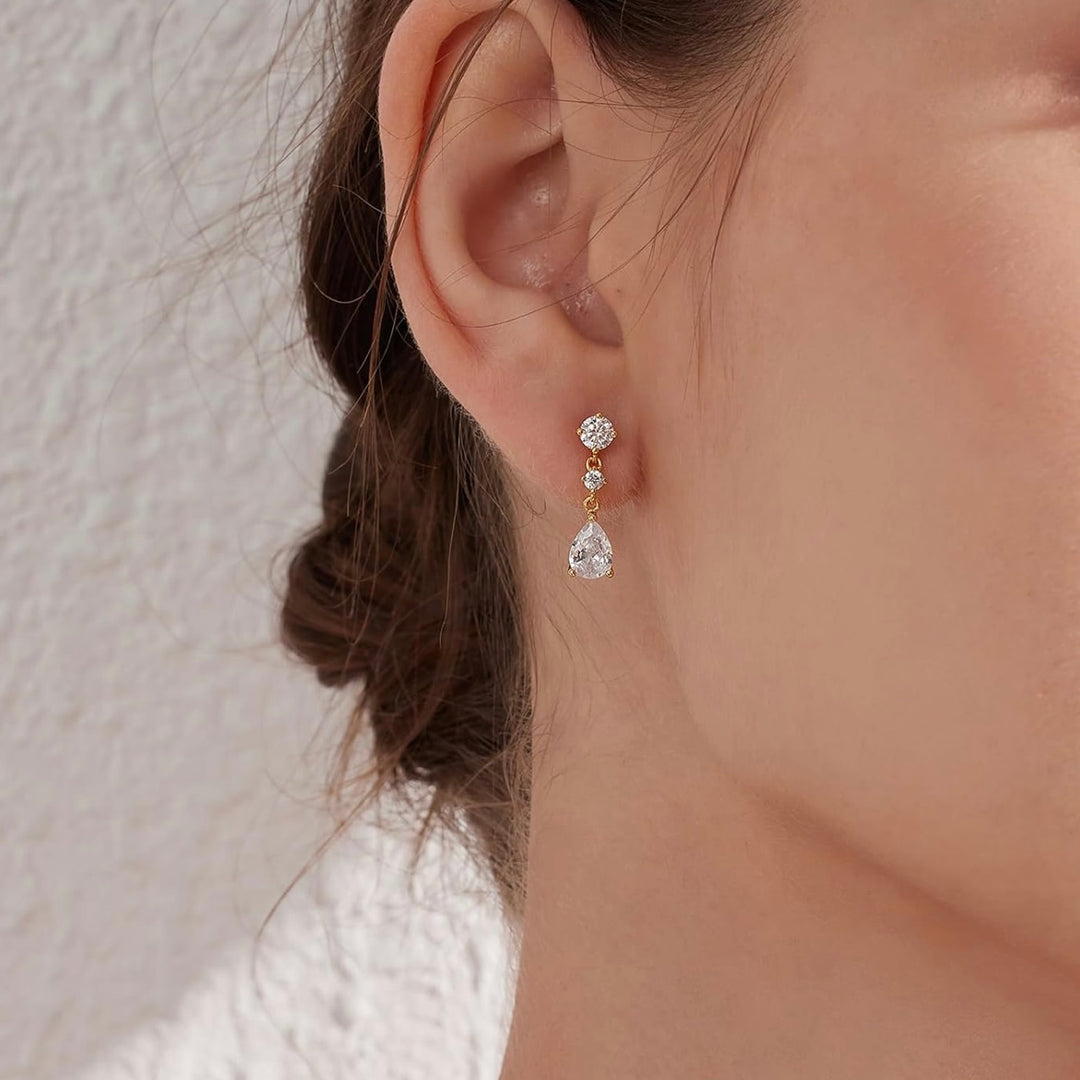Close-up of a person wearing a pair of earrings with a neutral background