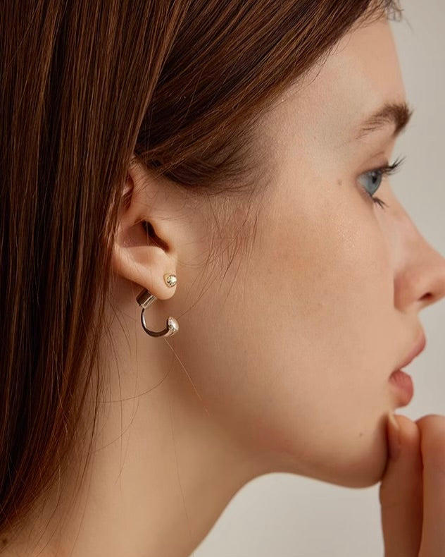 Close-up of a woman wearing a silver hoop earring on a neutral background