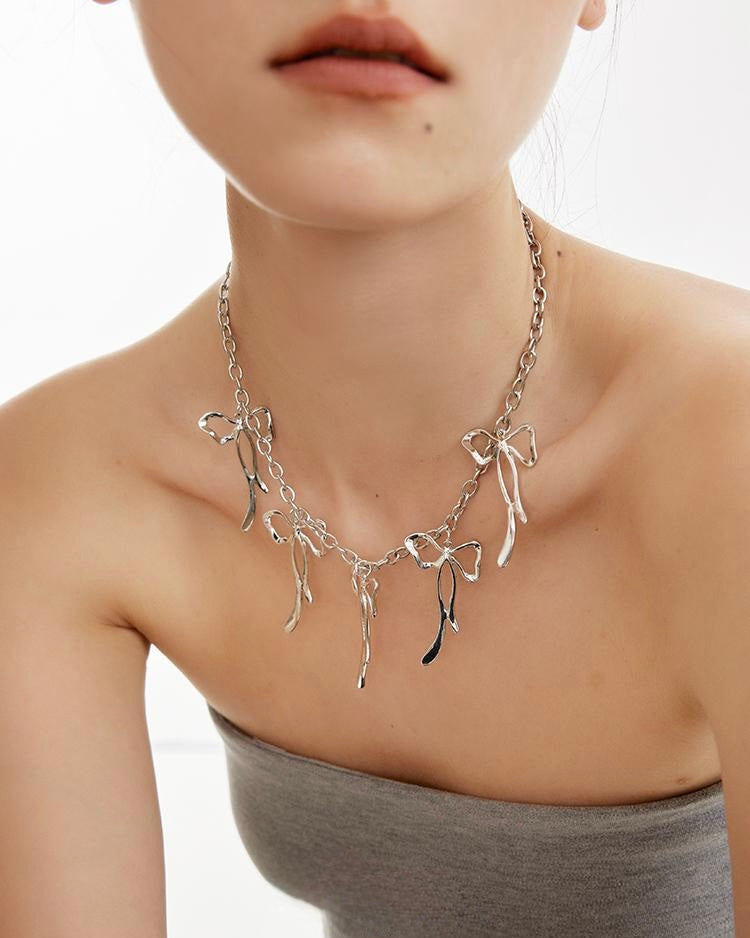 Ribbon Charm Necklace close-up showing bow pendant worn by model