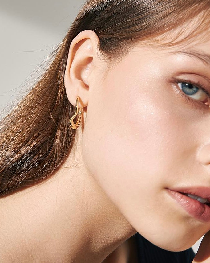 Wave Hoop Earrings close-up worn by model showing sculpted gold wave detail
